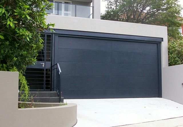 Modern garage door on a dark stone facade   professional installation by Koning Garage Doors